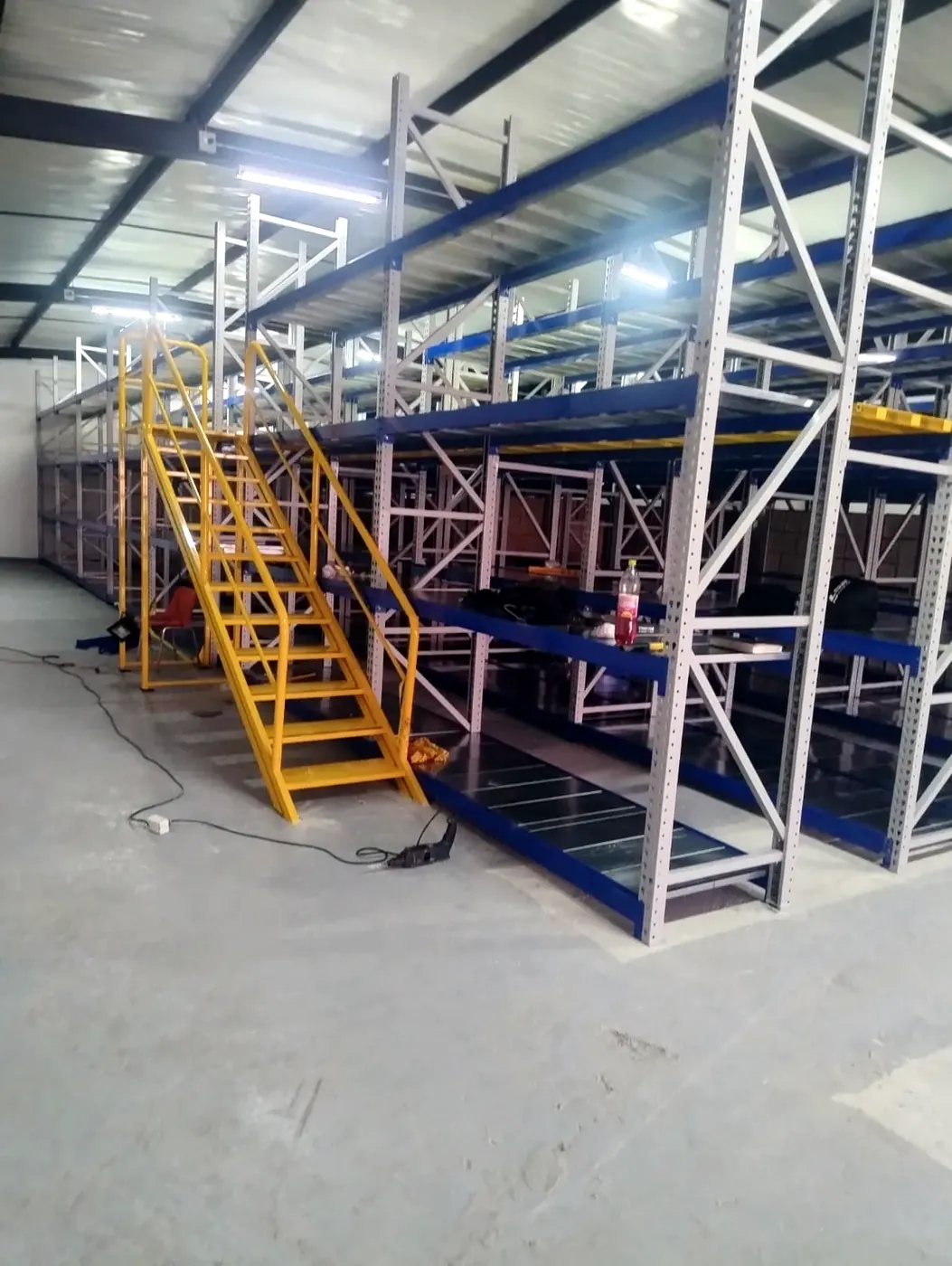 Bodega con mezzanine: Estanterías de carga pesada y mezzanine con escalera de acceso.